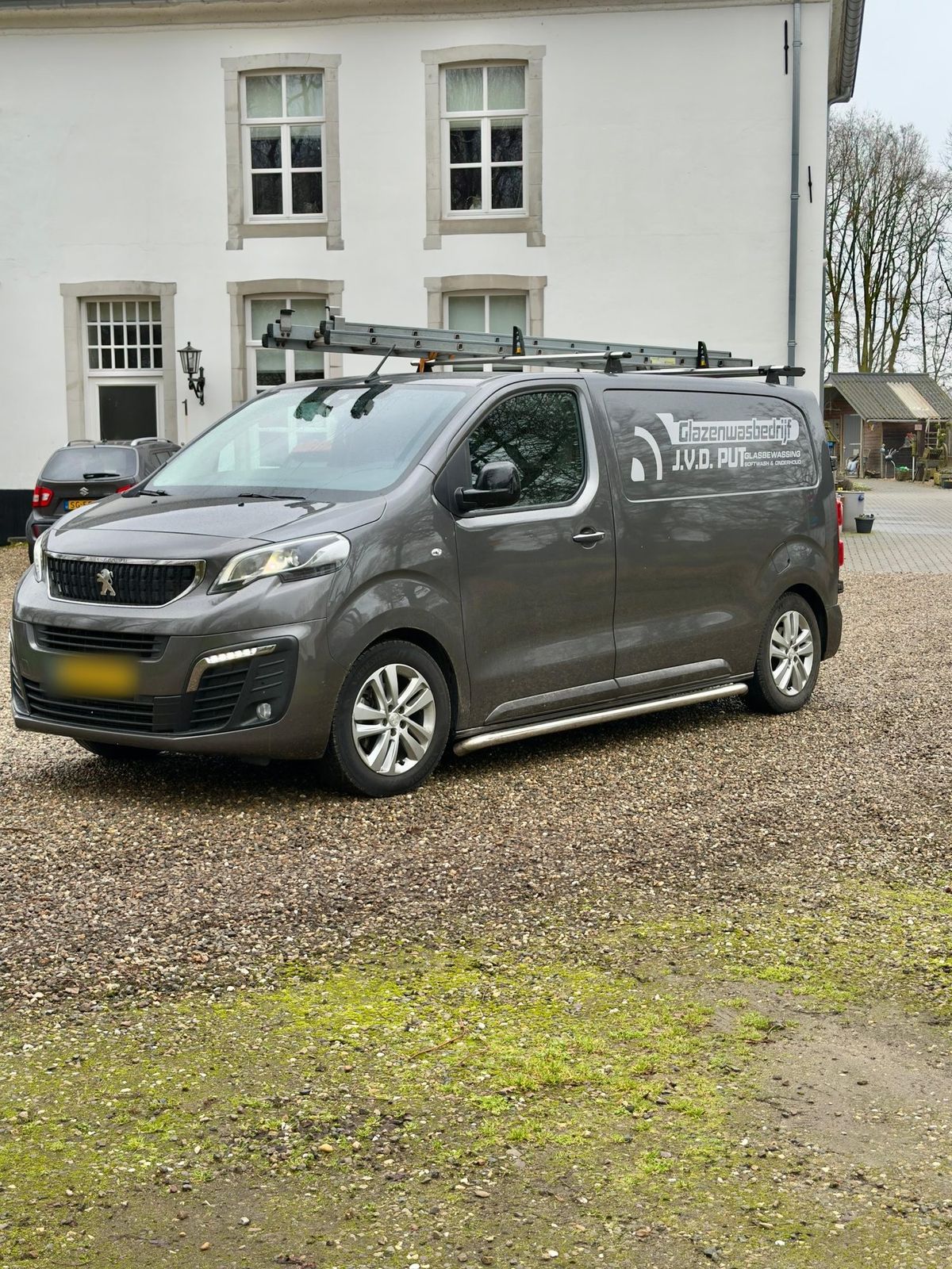 De grijze bedrijfsbus met de belettering Glasbewassing, Softwash en Onderhoud